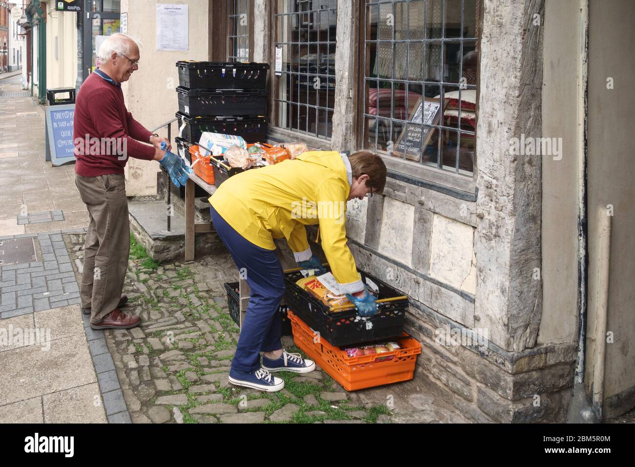Due volontari che raccolgono pacchetti alimentari e alimentari per la consegna a persone e case autoisolanti sotto il blocco, Presteigne, Powys, Galles, Regno Unito Foto Stock