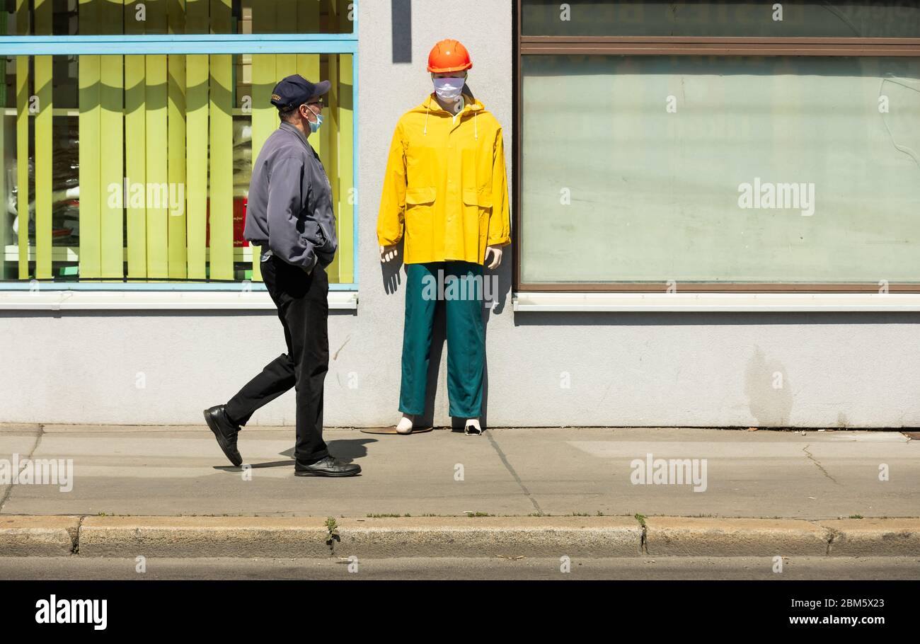 l'uomo con maschera protettiva sta camminando davanti ad un negozio di oggetti da lavoro protettivi Foto Stock