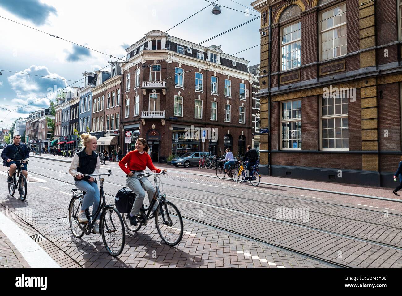 Amsterdam, Paesi Bassi - 8 settembre 2018: Strada con due ragazze in bicicletta nella città vecchia di Amsterdam, Paesi Bassi Foto Stock