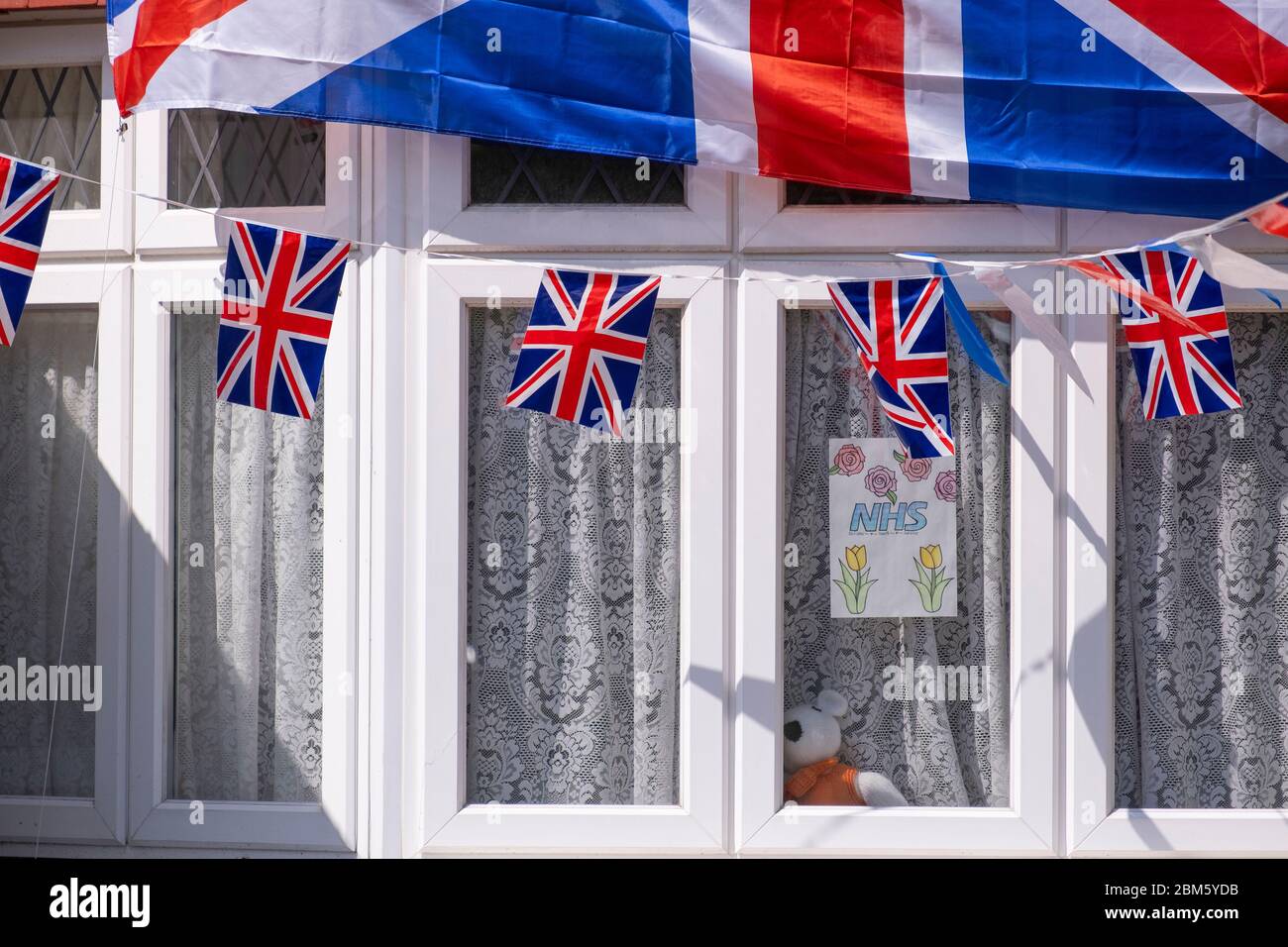 Morden, Surrey, Regno Unito. 7 maggio 2020. Finestra della baia di casa nel sud-ovest di Londra Borough di Merton sono ornati con bunting per celebrare il VE Day, anche con mano colorato grazie il poster NHS. Credit: Malcolm Park/Alamy Live News. Foto Stock