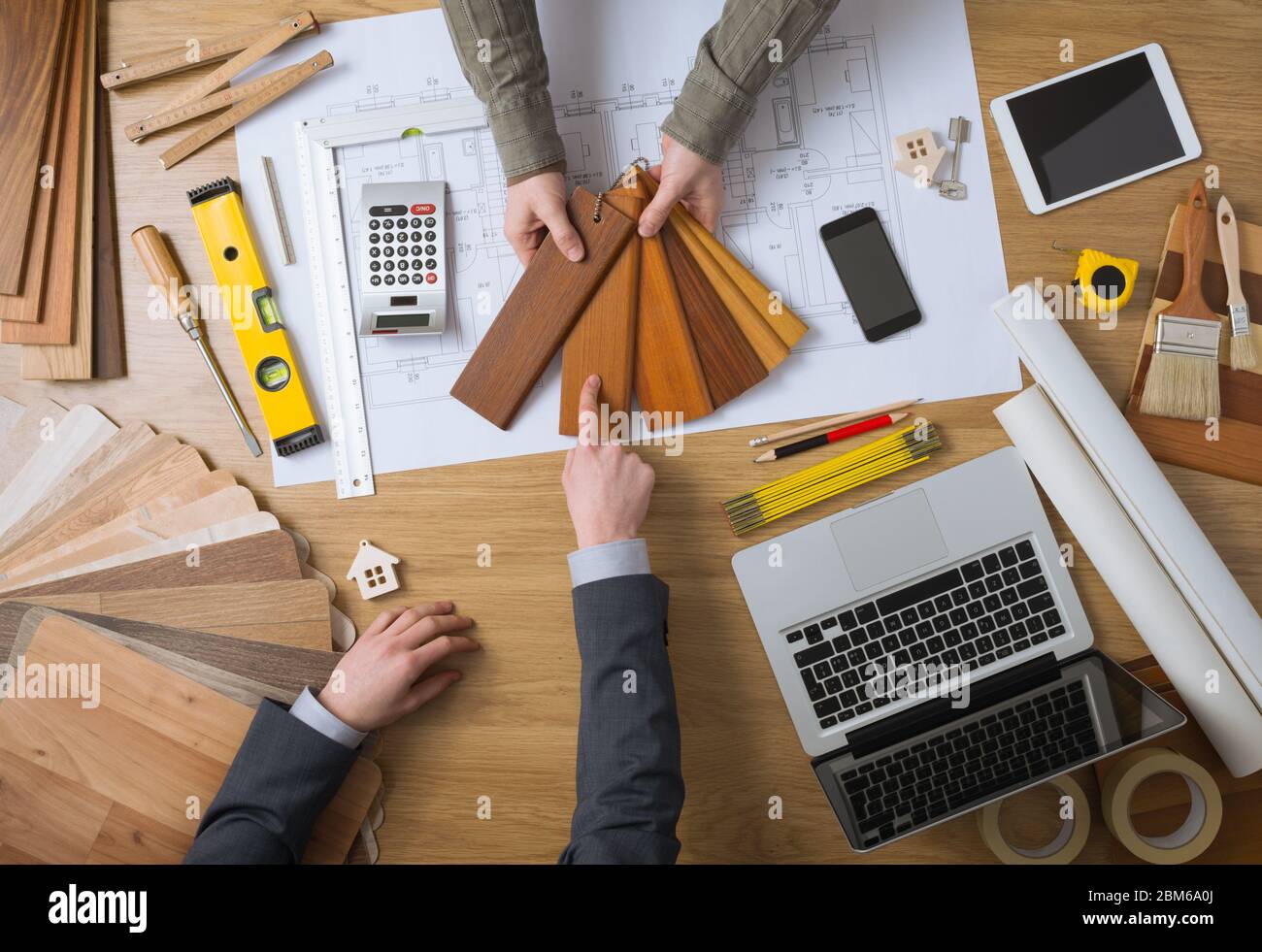 Interior designer che mostra i campioni di legno al suo cliente, laptop, strumenti e casa di progetti sul desktop di vista superiore Foto Stock