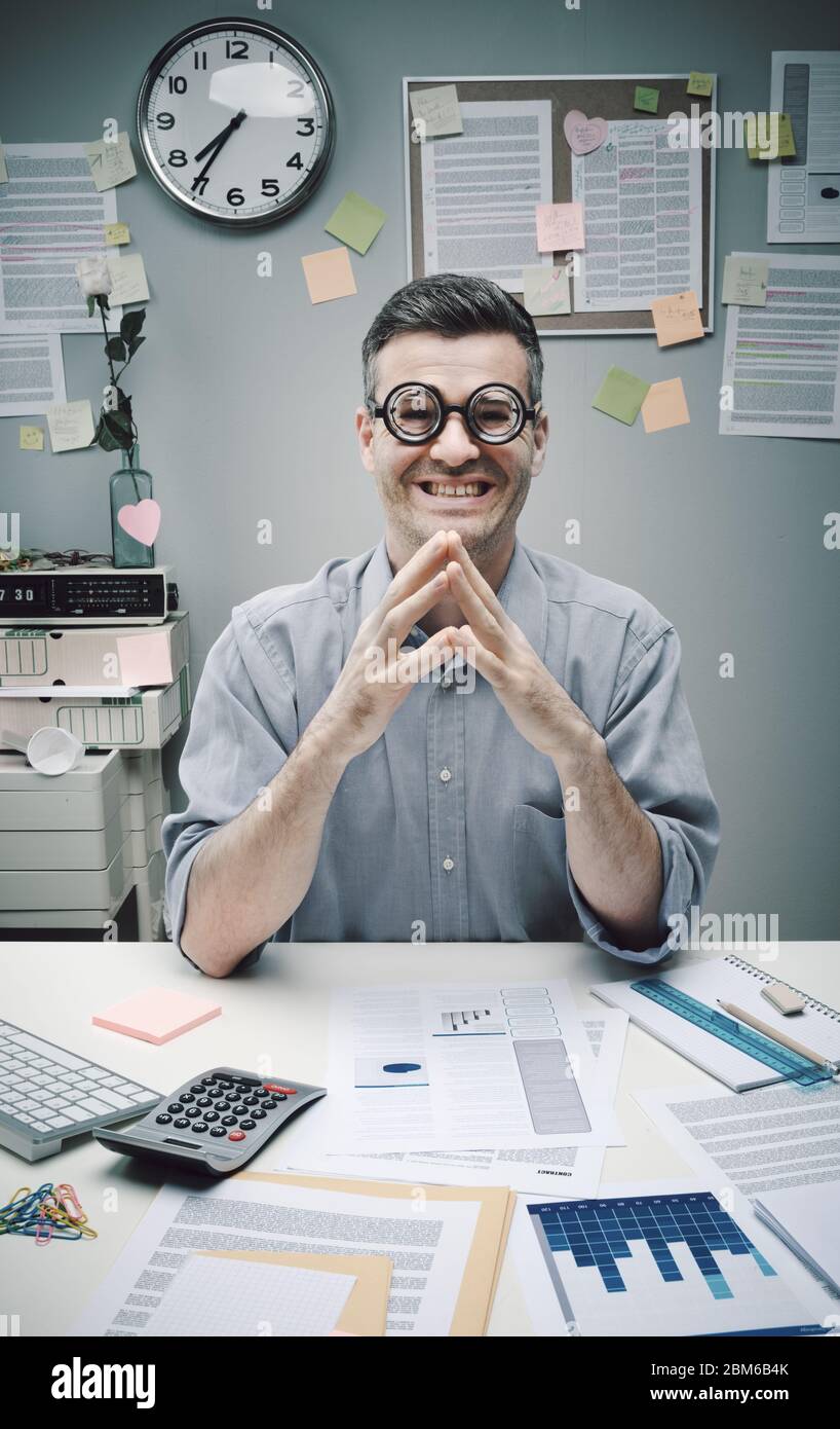Un uomo d'affari nero alla scrivania con occhiali spessi sorridendo alla macchina fotografica. Foto Stock