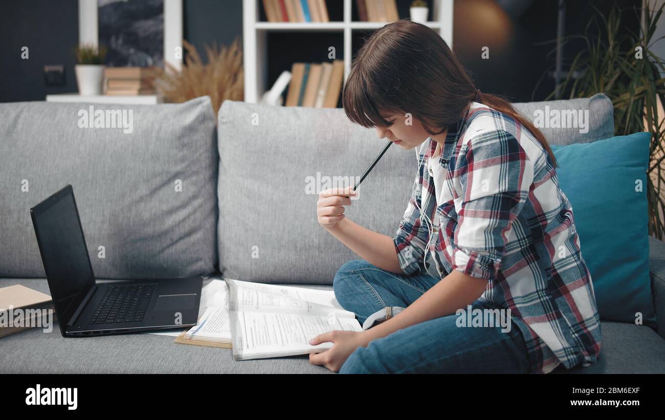 Adolescente che fa i compiti sul divano Foto Stock