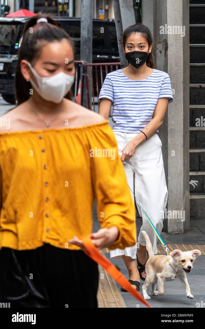 Ragazza con maschera di viso cane da passeggio durante Covid 19 pandemic, Bangkok, Thailandia Foto Stock