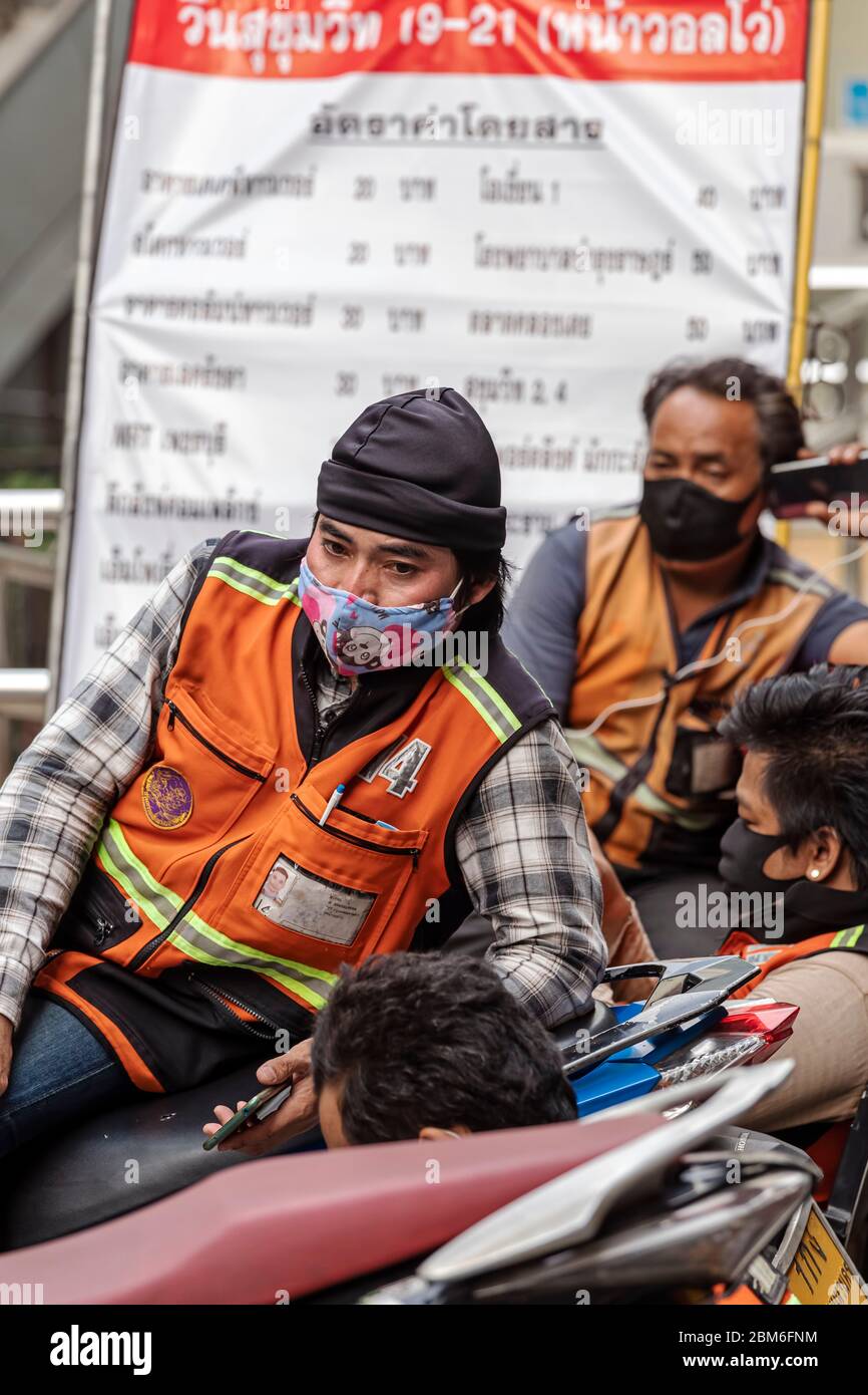 Motociclista con maschera facciale in attesa di clienti durante Covid 19 pandemic, Bangkok, Thailandia Foto Stock