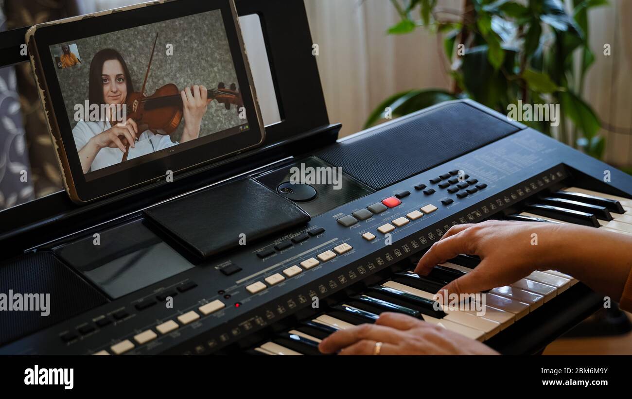 Violinista e pianista giocano insieme su Internet, essendo isolatamente per la pandemia del coronavirus Foto Stock