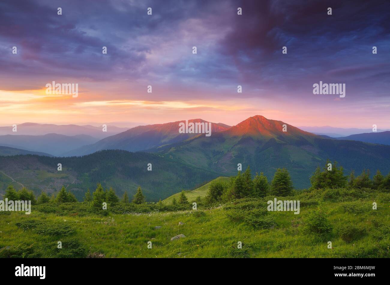 Paesaggio estivo con mattinata colorata. I primi raggi del sole sulle cime della montagna. Carpazi rumeni Foto Stock