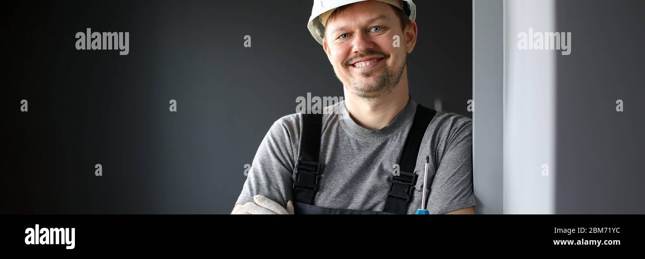 Maschio costruttore in tute e elmetto sorridente Foto Stock