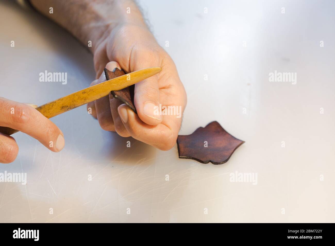 Finitura bordo pelle con utensili realizzati a mano. Il processo di fabbricazione di un portafoglio in pelle fatto a mano. L'artigiano cucisce una pelle Foto Stock