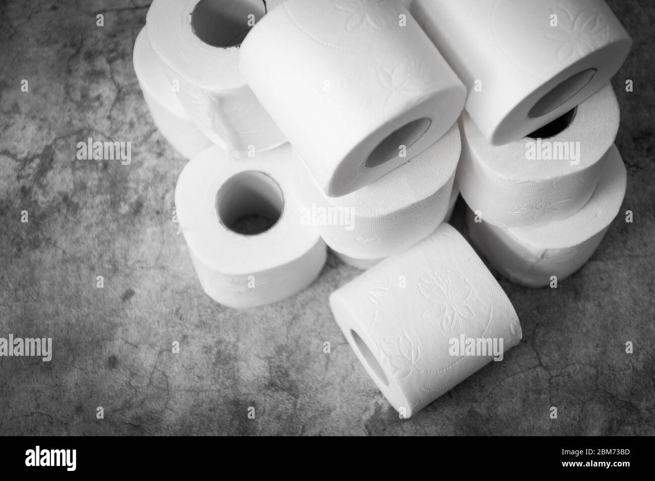 Tre rotoli di carta igienica su sfondo grigio chiaro. Mancanza di articoli di igiene di base Foto Stock