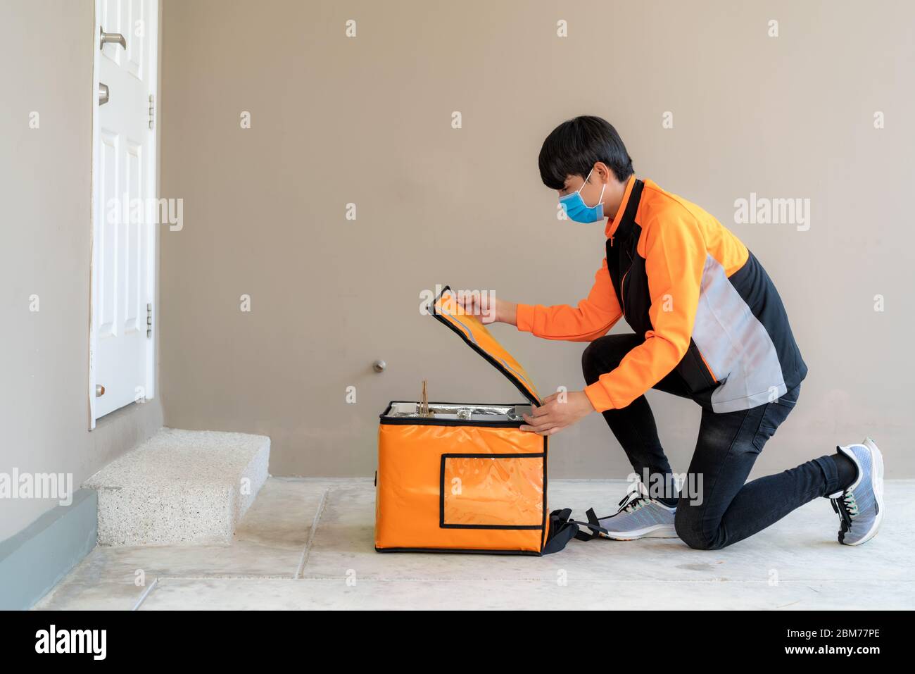 Consegna asiatica uomo goccia e open consegna alimenti scatola per contactless o contatto libero in casa per sociale distanza per il rischio di infezione. Foto Stock