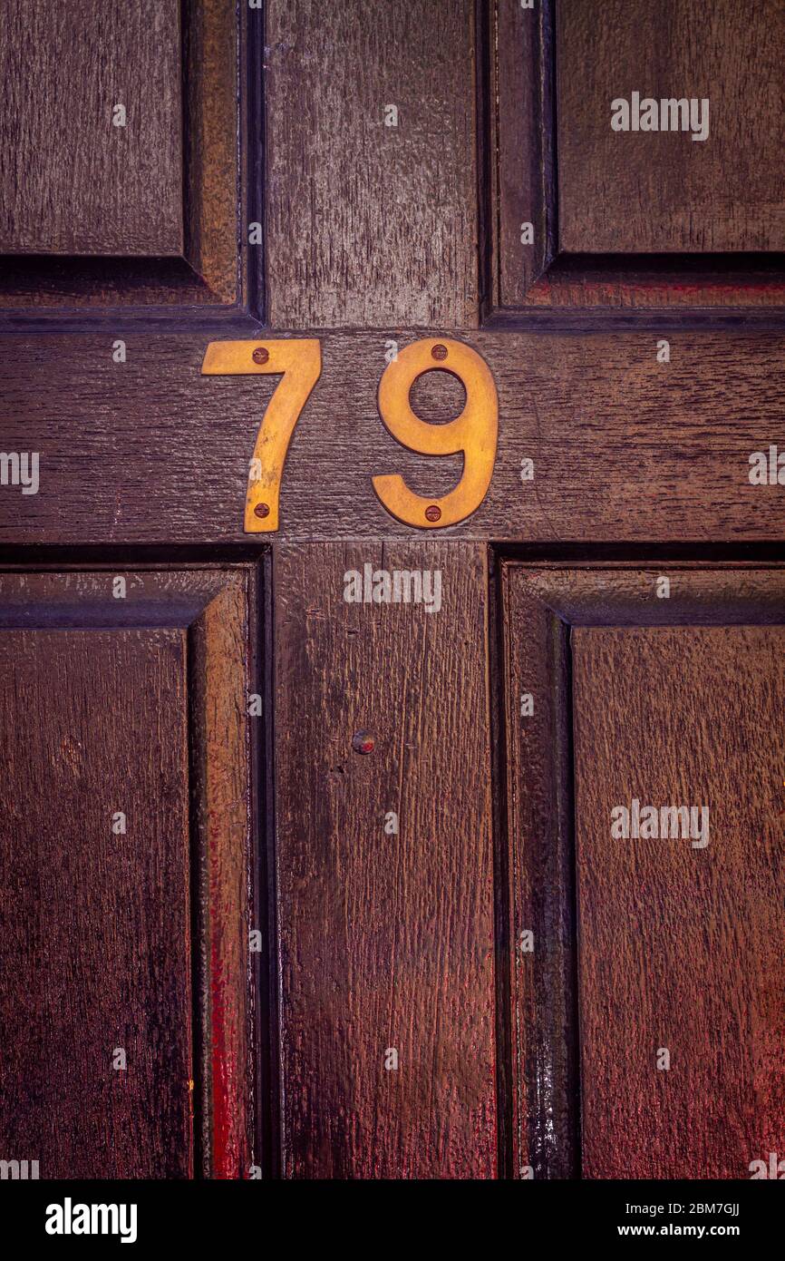 Casa numero 79 su una porta anteriore in legno verniciato scuro Foto Stock