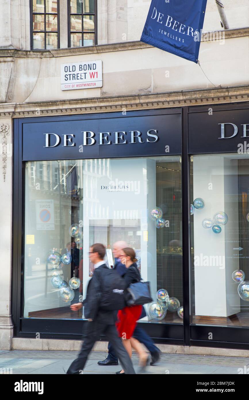 Tre uomini d'affari vestiti con eleganza camminano davanti al lussuoso negozio di gioielli De Beers in Old Bond Street, nel West End di Londra Foto Stock
