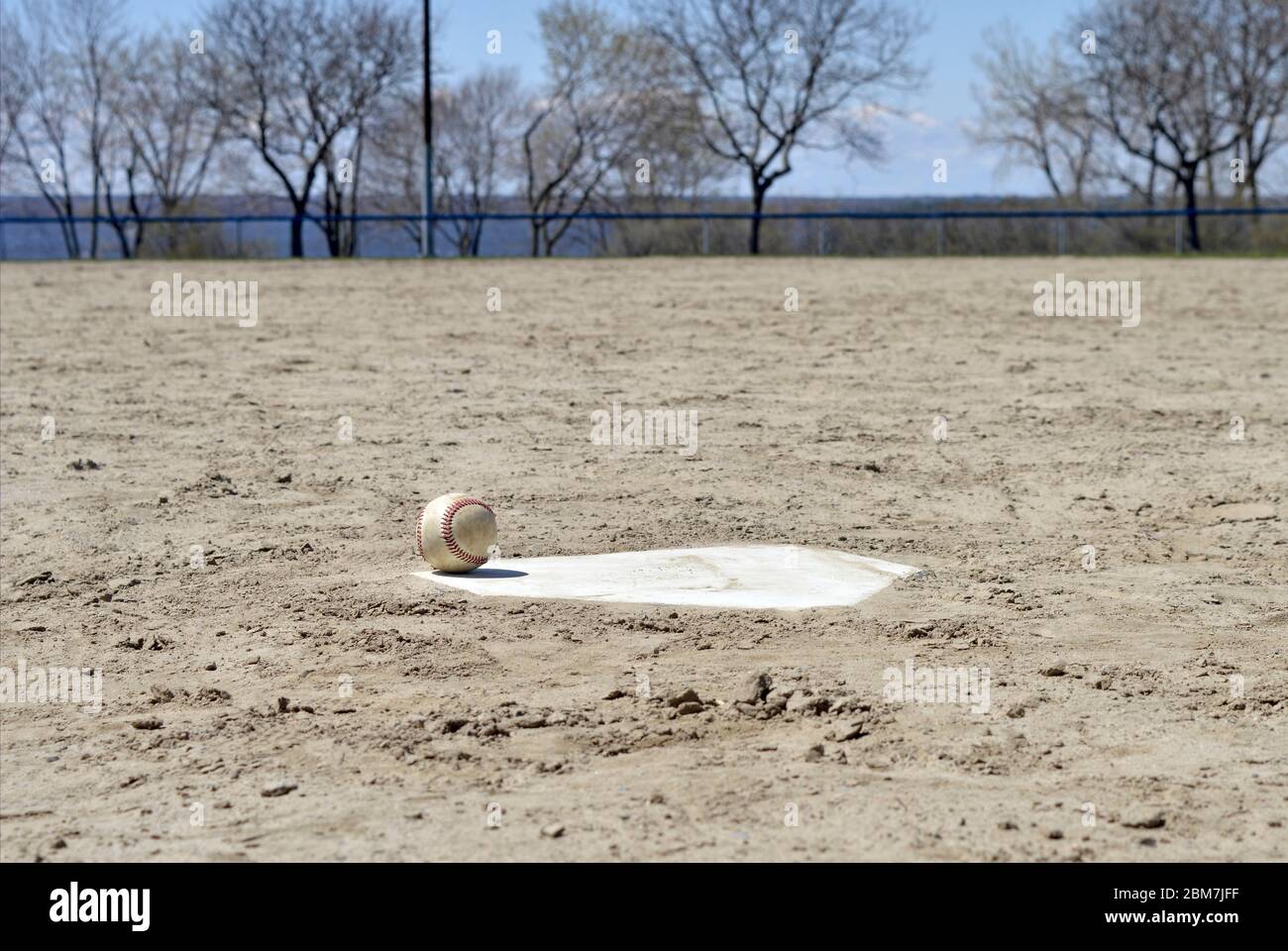 Un baseball si siede sul piatto della casa - senza gente intorno per giocare lo sport. I parchi sono stati chiusi per incontri pubblici sia professionali che amatoriali. Foto Stock