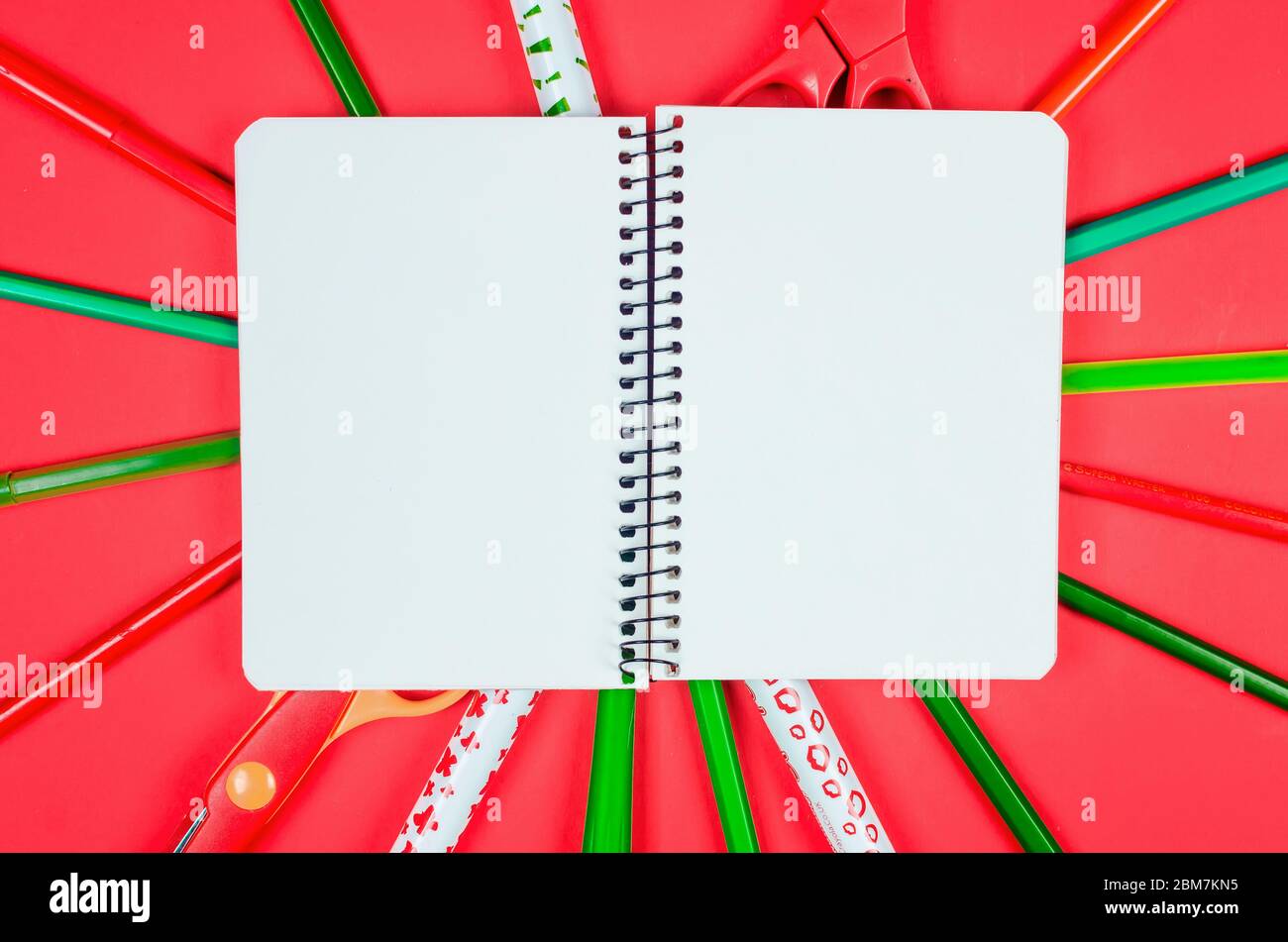 Notebook, forniture scolastiche colorate su sfondo rosso. Concetto di istruzione. Vista dall'alto con spazio per la copia. Mockup, piatto Foto Stock