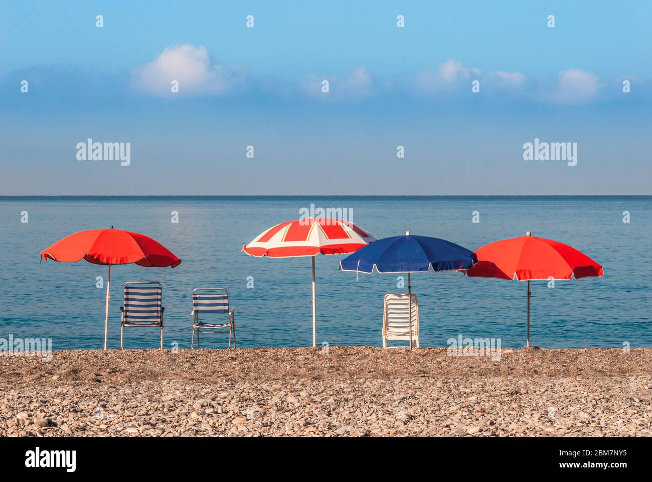 Ombrelloni e sedie che si affacciano sull'orizzonte mediterraneo del mare sulla spiaggia vuota di la Herradura, Costa Tropical, Andalusia, Spagna Foto Stock
