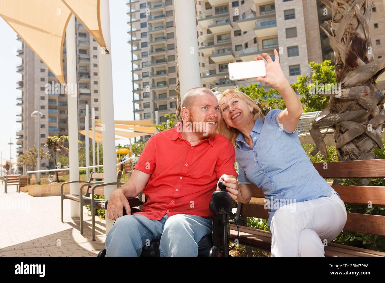 Un vero uomo disabili su sedia a rotelle si diverte con una donna graziosa Foto Stock