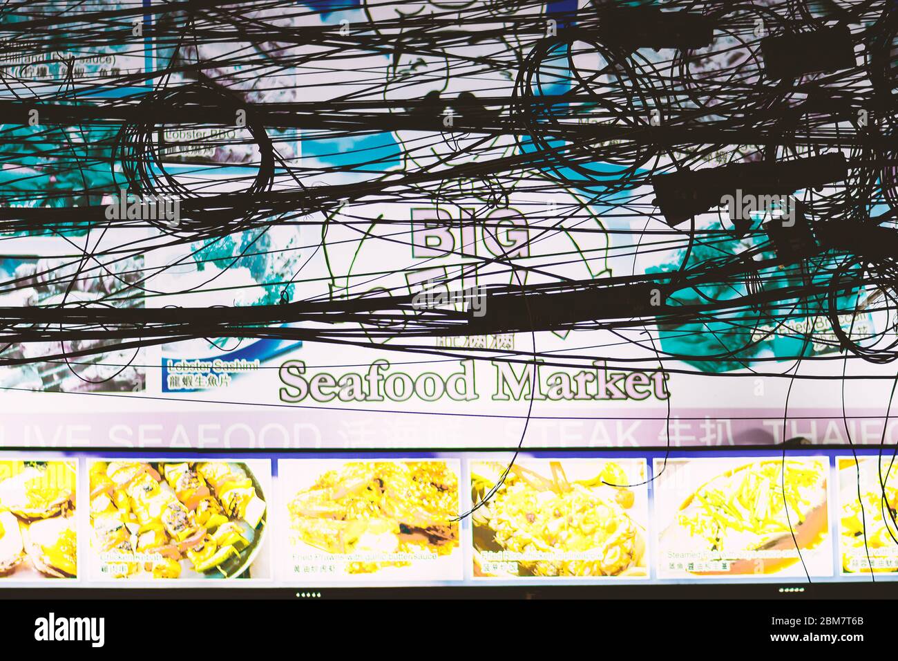 Thailandia Samui 9 MAR 2020 Big Belly frutti di mare mercato cartellone in primo piano di fili neri silhouette di notte. La Affissioni è sfocata Foto Stock