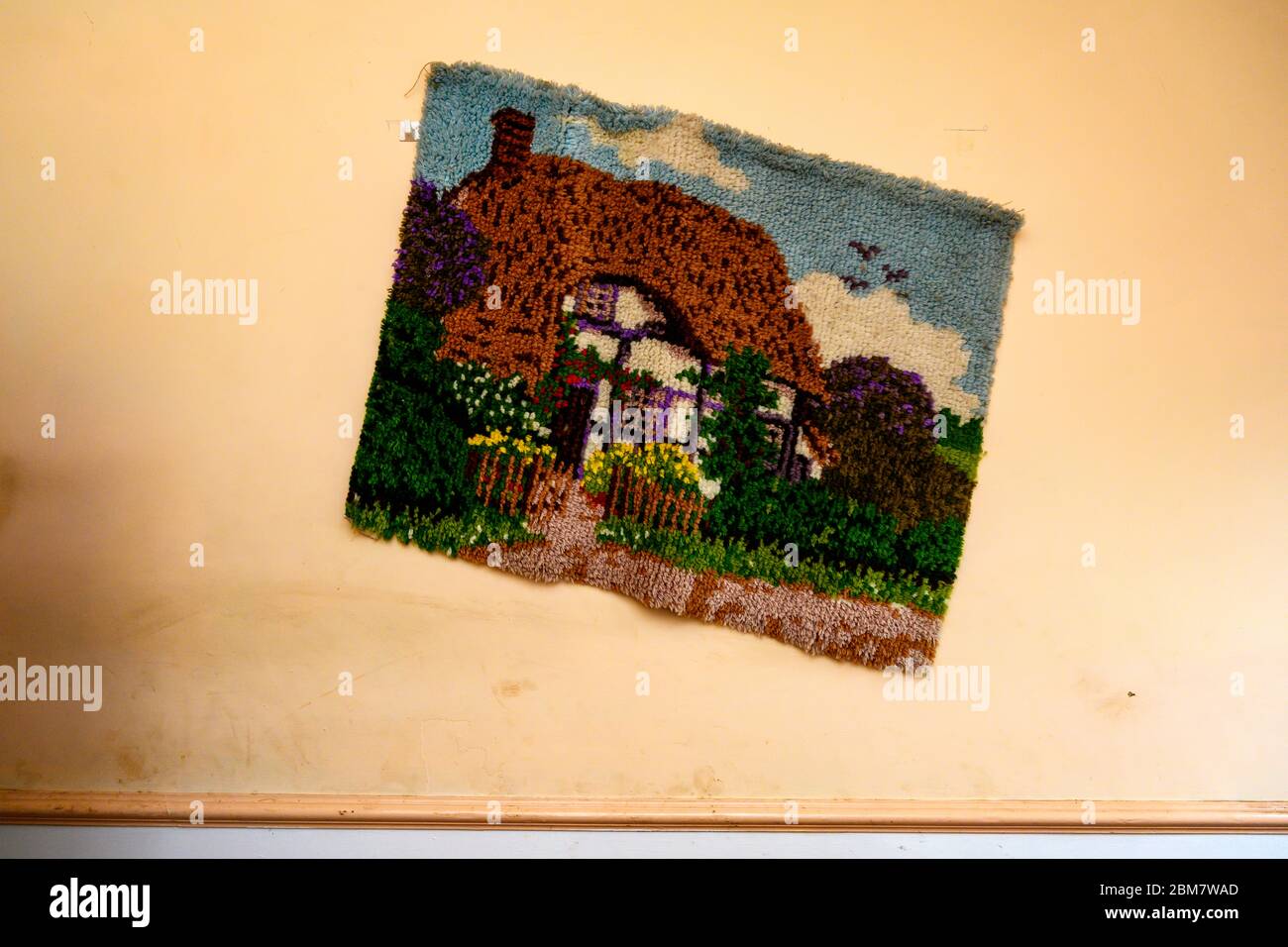 Needlecraft di un cottage di campagna con tetto di paglia appeso su un muro Foto Stock