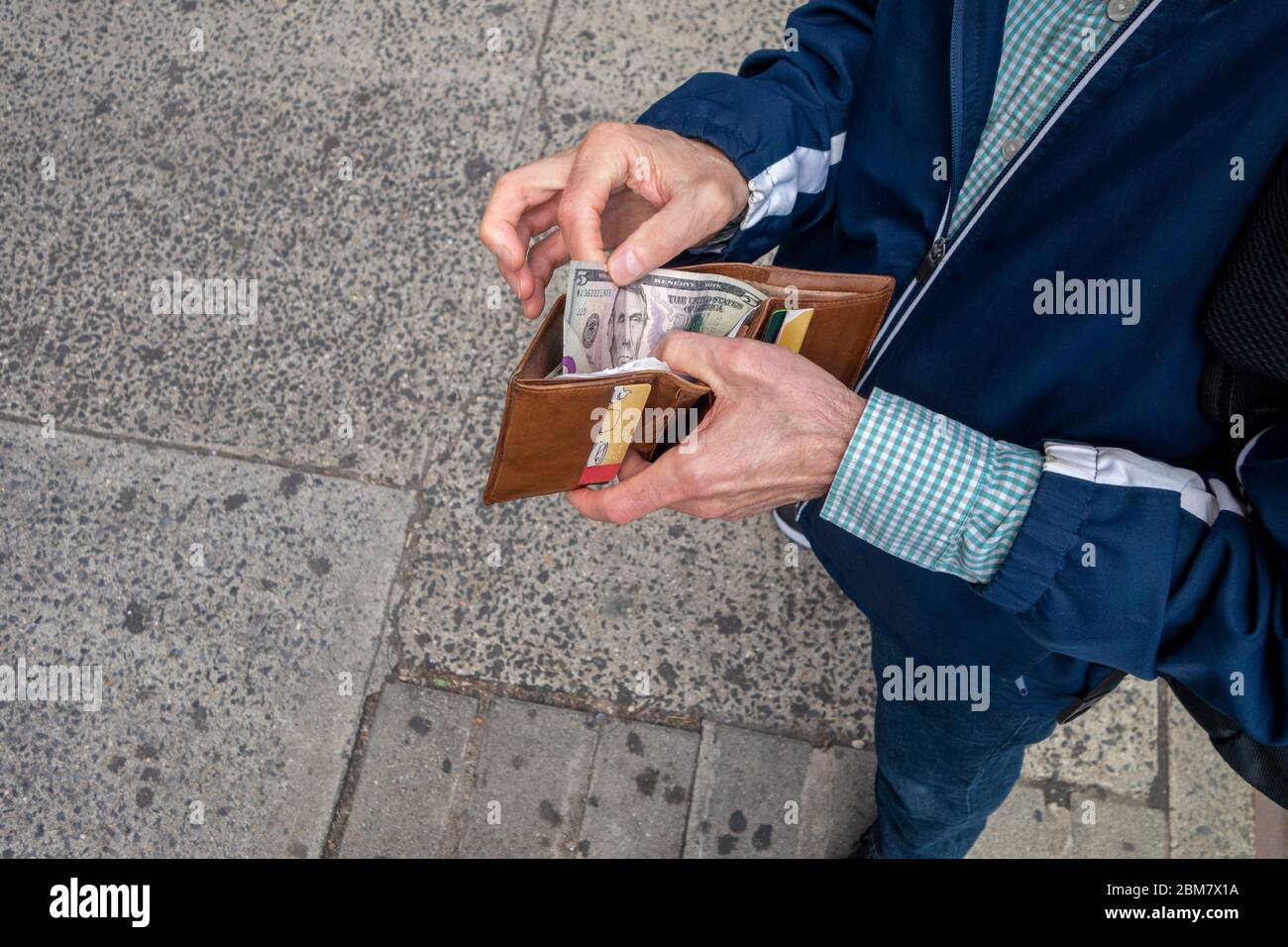 Guardando verso il basso un uomo pronto a fare un pagamento in contanti con denaro in contanti americano fattura di venti dollari Foto Stock