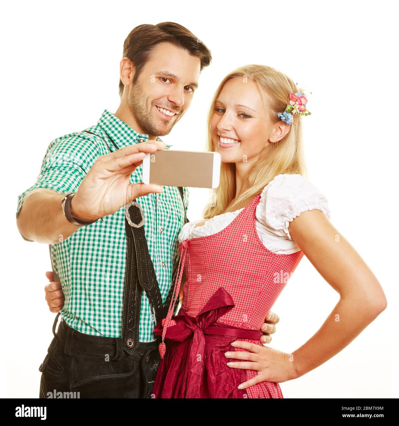 Felice coppia in abiti tradizionali bavaresi fotografarsi con uno smartphone Foto Stock