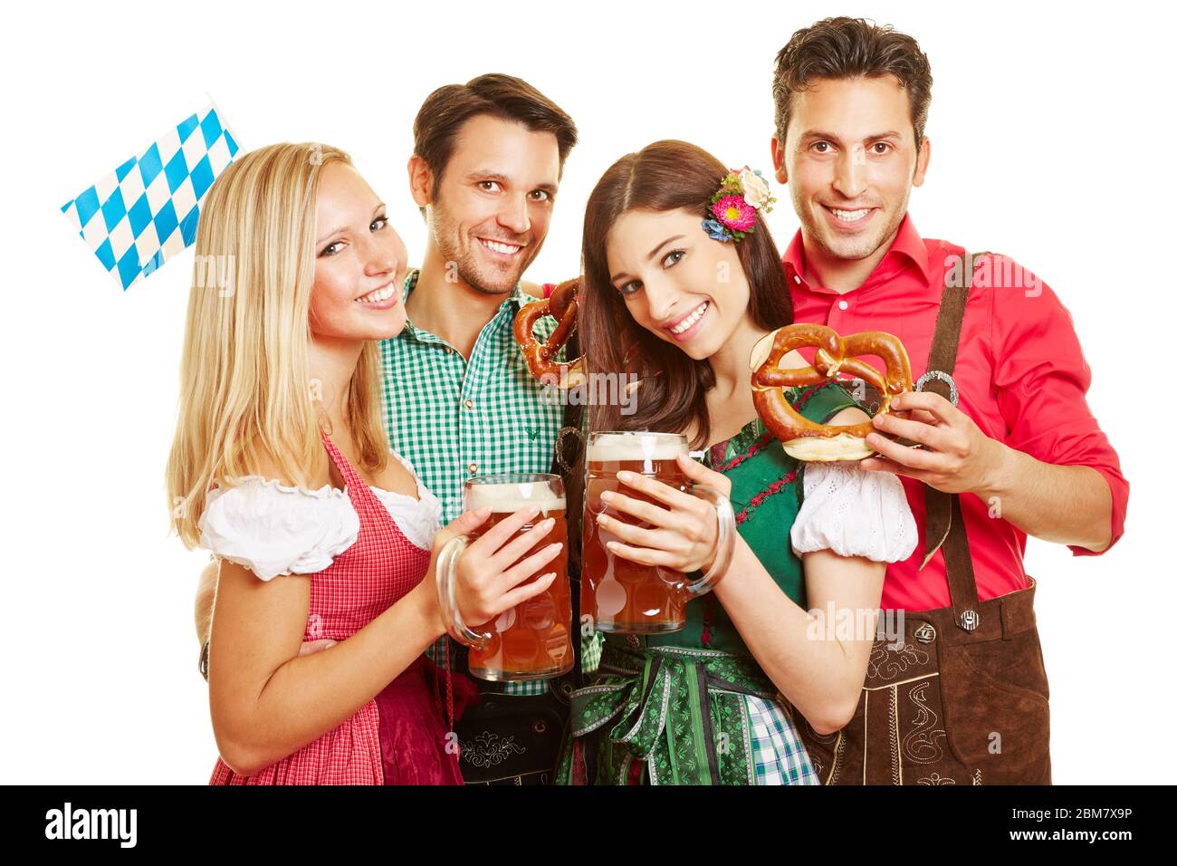 Quattro amici felici all'Oktoberfest festeggiano in dirndls e lederhosen con pretzel e birra Foto Stock