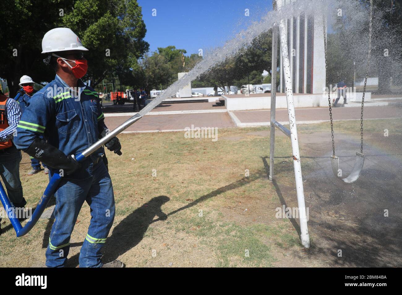 I lavoratori del consiglio comunale svolgono lavori di sanificazione a causa della pandemia di Covid 19, utilizzando liquidi pressurizzati per pulire la piazza pubblica di Niños Héroes. Giocano giochi per bambini, alberi, una statua e monumenti per gli eredi dell'indipendenza del Messico: Juan de la Barrera, Juan Escutia, Agustín Melgar, Fernando Montes de Oca, Vicente Suárez e Francisco Márquez. Hermosillo, sonora al 7 maggio 2020. (Foto: Luis Gutierrez / NortePhoto.com) Trabajadores del ayuntamiento realizan trabajos de sanitización de vido a la pandemia del Covid 19 usando líquidos a pressionion para limpiar la plaza pubica ni Foto Stock