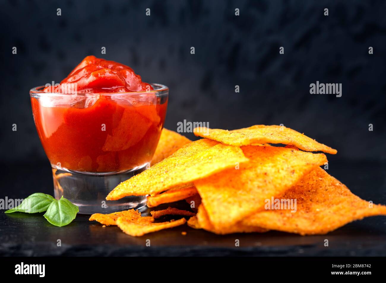 Tortilla chips e una ciotola di vetro riempita con salsa di salsa Foto Stock