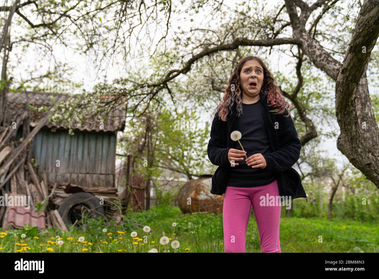Ragazza bruna giocosa in giacca nera e abito rosa facendo divertente viso Foto Stock