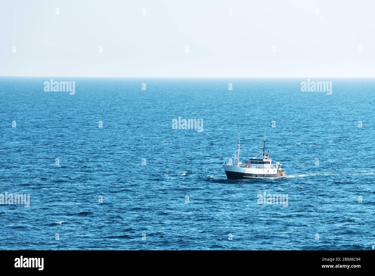 Solitario nave da pesca a strascico sulla barca di acqua oceanica. Calma il mare limpido tempo soleggiato. Bellissimo orizzonte di seascape Foto Stock