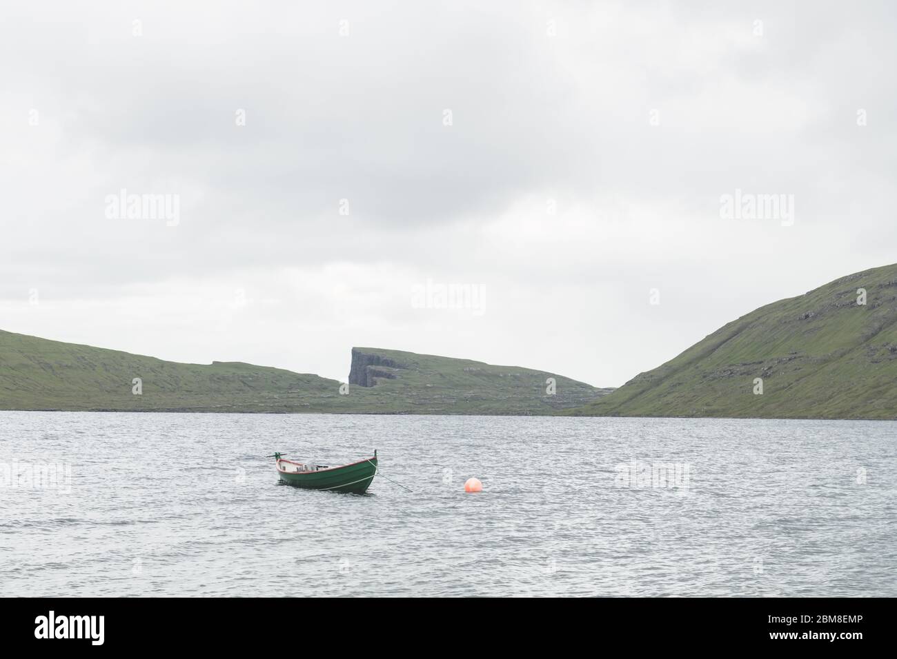 Vista mattutina su una barca solitaria sul lago nuvoloso Sorvagsvatn sulle scogliere dell'isola di Vagar, Isole Faroe, Danimarca. Fotografia di paesaggio Foto Stock