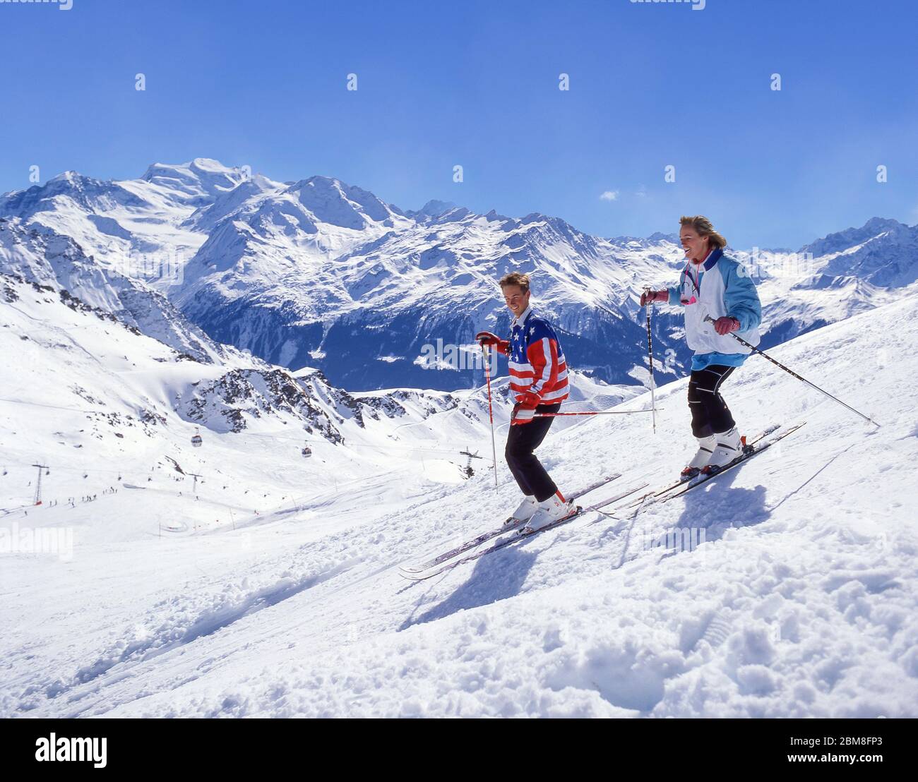 Giovane coppia sciare giù pista, Verbier, Canton du Vallese, Svizzera Foto Stock