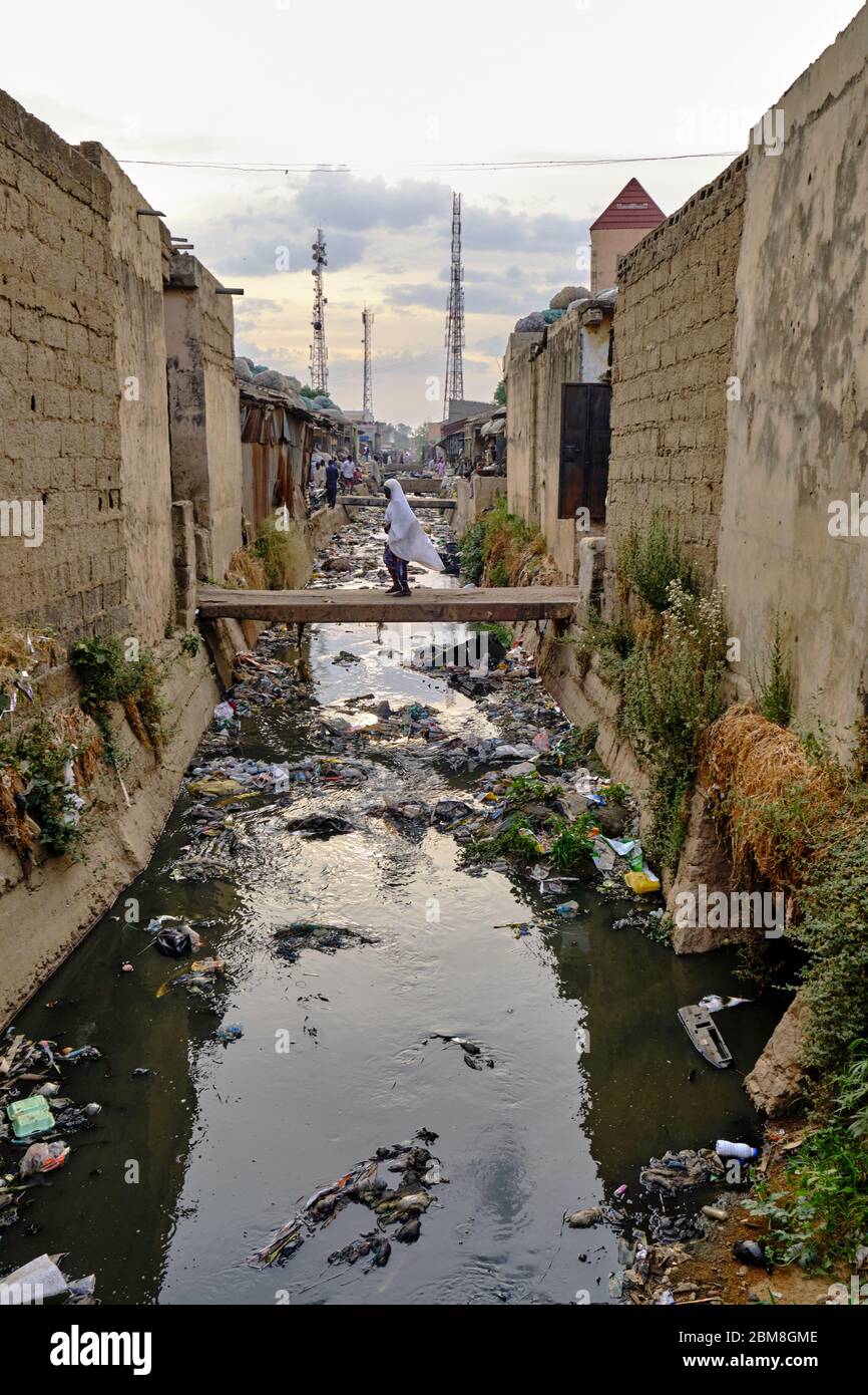 Ragazza che cammina su un ponte sui canali inquinati del mercato di via Kano. Foto Stock