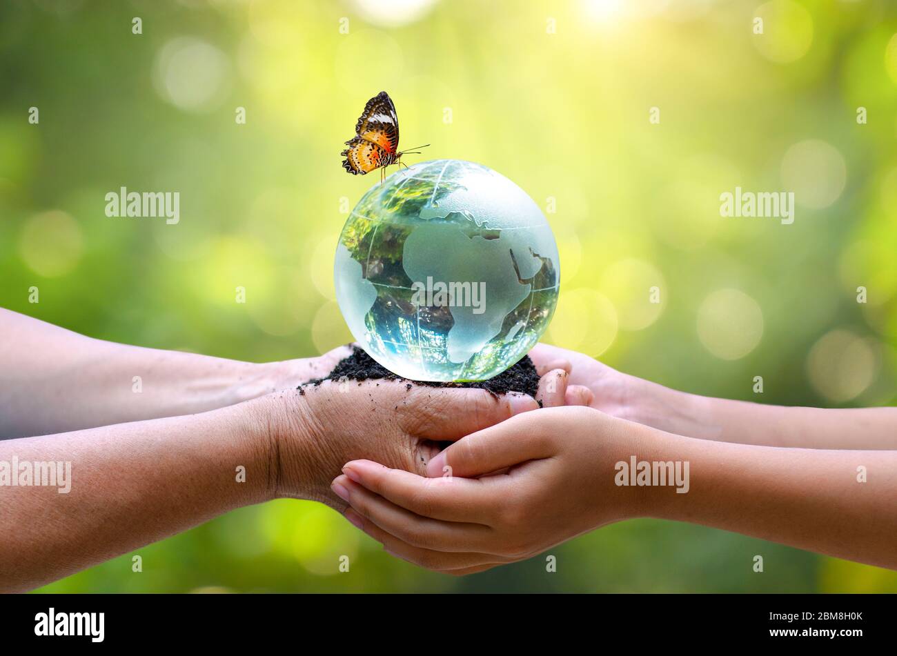 Gli adulti stanno inviando il mondo ai bambini. Concetto giorno Terra salvare il mondo salvare l'ambiente il mondo è nell'erba del verde sfondo bokeh Foto Stock