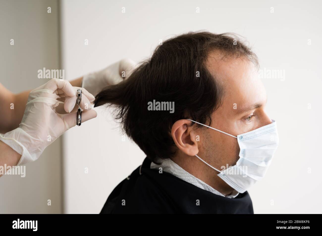 Uomo che taglia i capelli corti al salone in maschera facciale Foto Stock
