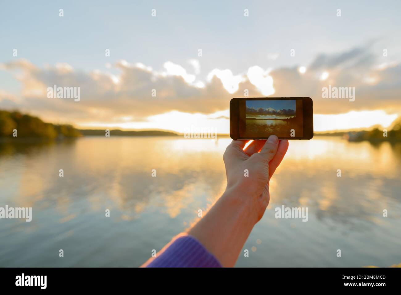 Mani di giovane uomo che scatta foto con telefono di bellissimo tramonto Foto Stock