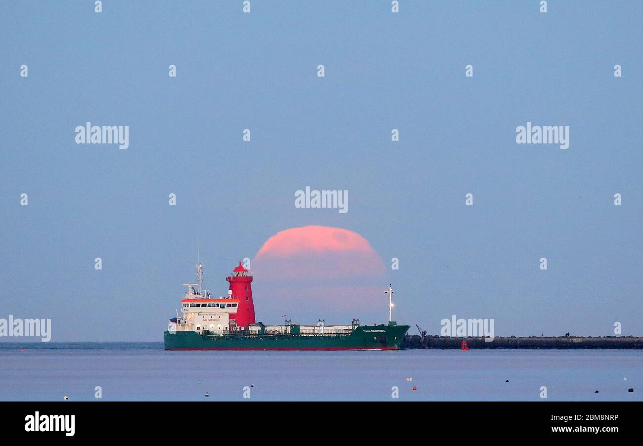 L'ultima superluna dell'anno sorge sopra il faro di Poolbeg nella baia di Dublino, in Irlanda. La luna piena di maggio è anche conosciuta come la "luna di fiori", che significa i fiori che fioriscono durante il mese. Data foto: Giovedì 7 maggio 2020. La luna piena di questo mese è anche una superluna, il che significa che sarà circa il 6% più grande di una luna piena tipica e circa il 14% più grande di una microluna, che è quando la luna è al suo punto più lontano dalla Terra. Vedi la storia della PA SCIENCE Supermoon. Il credito fotografico dovrebbe leggere: Brian Lawless/PA Wire Foto Stock