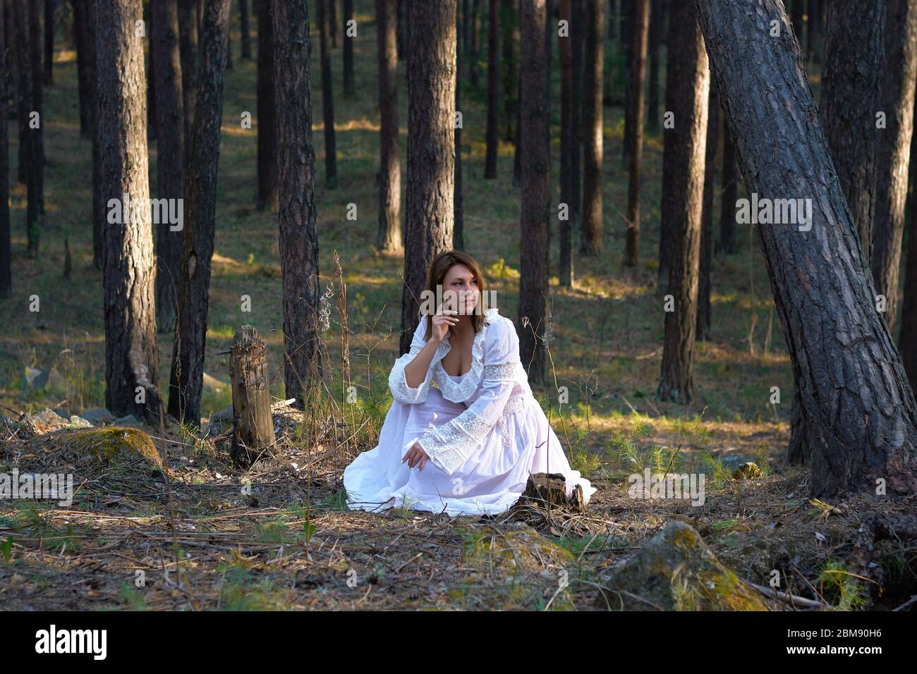 ragazza in un vestito bianco nella foresta al tramonto Foto Stock