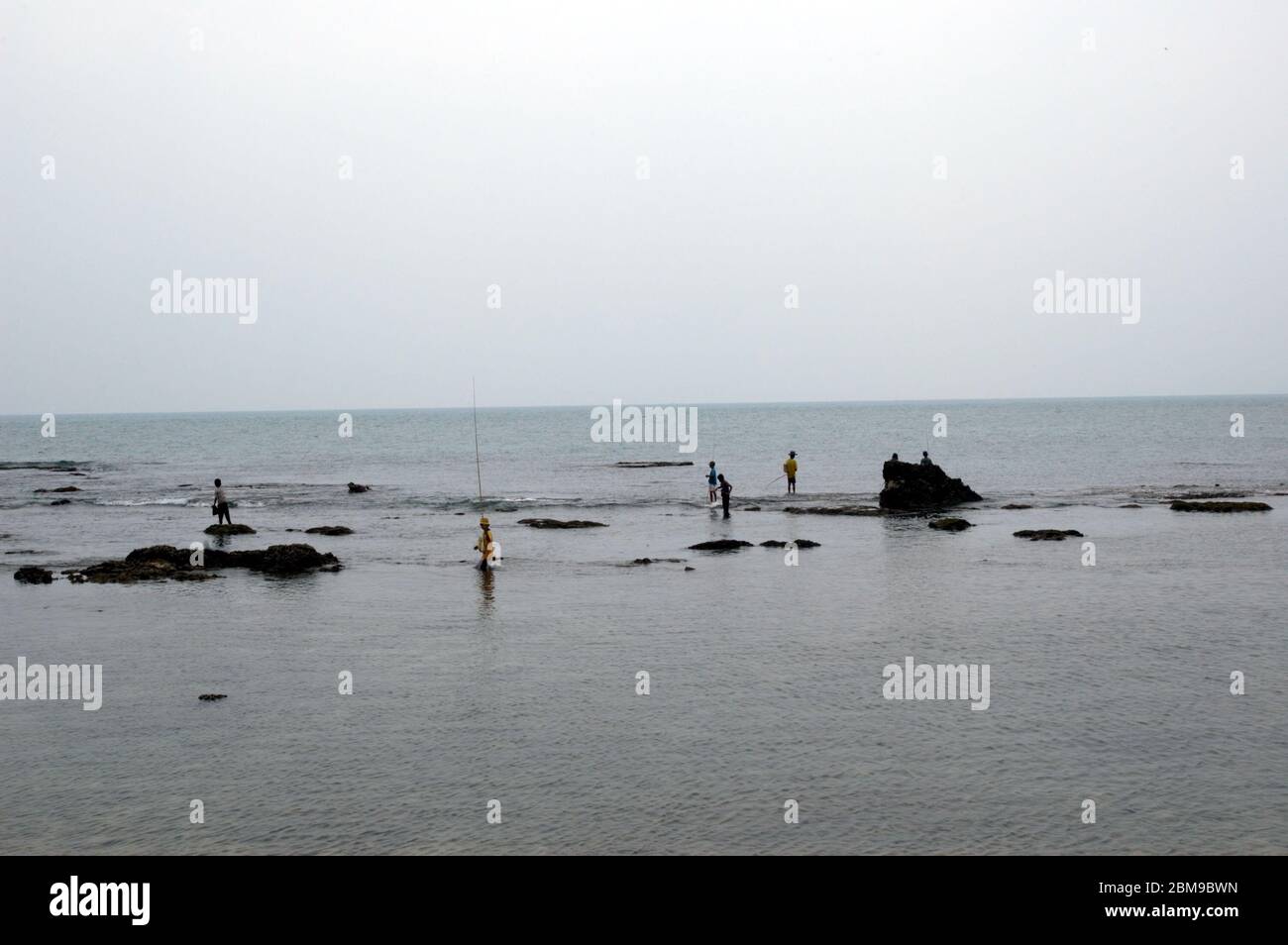 Uomini che pescano sulla zona costiera rocciosa vicino al Faro di Cikoneng ad Anyer, una città costiera di fronte allo stretto di Sunda nella provincia di Banten, Indonesia. Foto di archivio. Foto Stock