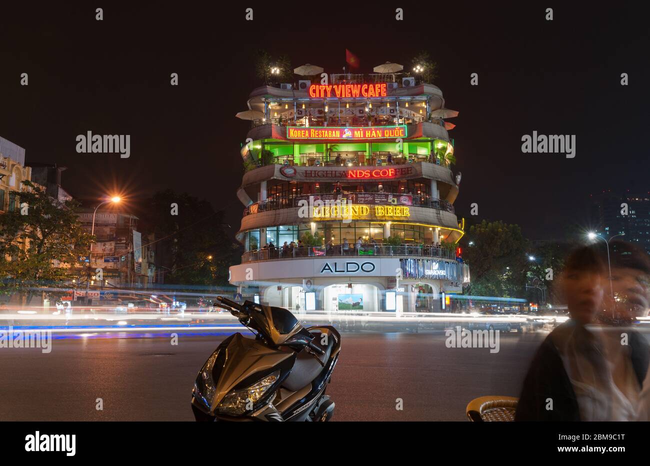 Hanoi Vietnam Ottobre 24 2013; Hanoi notte strada scena con edificio moderno illuminato con segnaletica neon, mentre le luci ruscelli e sfocature dal passaggio Foto Stock