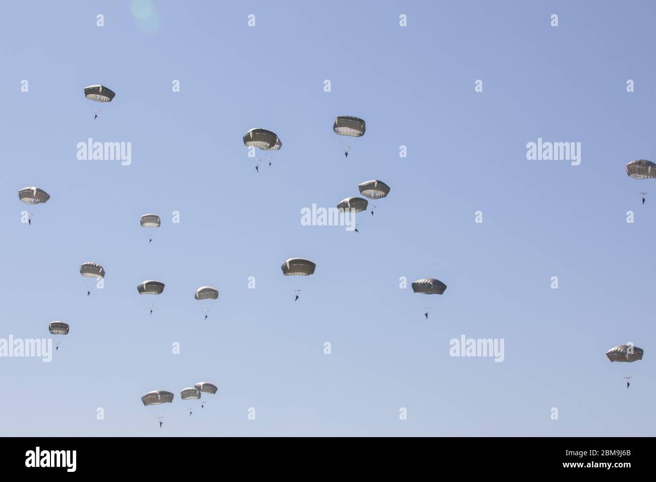 Paratroopers of the 82nd Airborne Division descend after jumping from an aircraft during an airborne operation on Fort Bragg, NC, May 7, 2020. The Airborne Operation marks the 82nd Airborne Division’s return to limited training operations while following health and safety guidelines to prevent the spread of the novel coronavirus.  Paratroopers were required to wear masks while in close proximity to each other and Jumpmasters wore masks while conducting inspections in the passenger terminal. (U.S. Army photo by Sgt. 1st Class Zachary J. VanDyke) Foto Stock