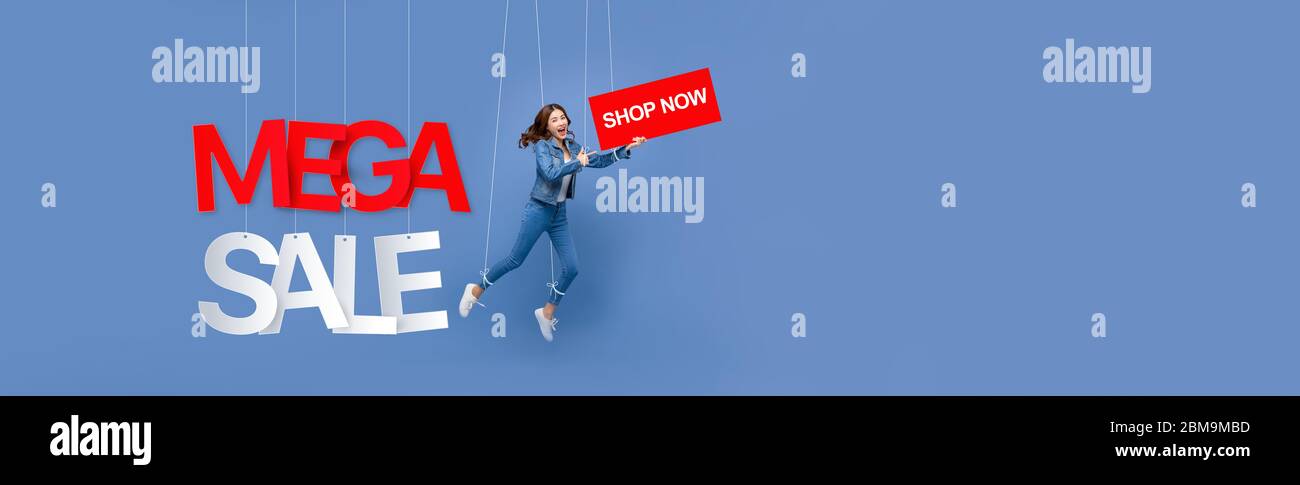 Eccitato bella donna asiatica pupet su corde tenuta ACQUISTA ora segno con MEGA VENDITA testi appesi su sfondo chiaro blu banner con spazio copia Foto Stock