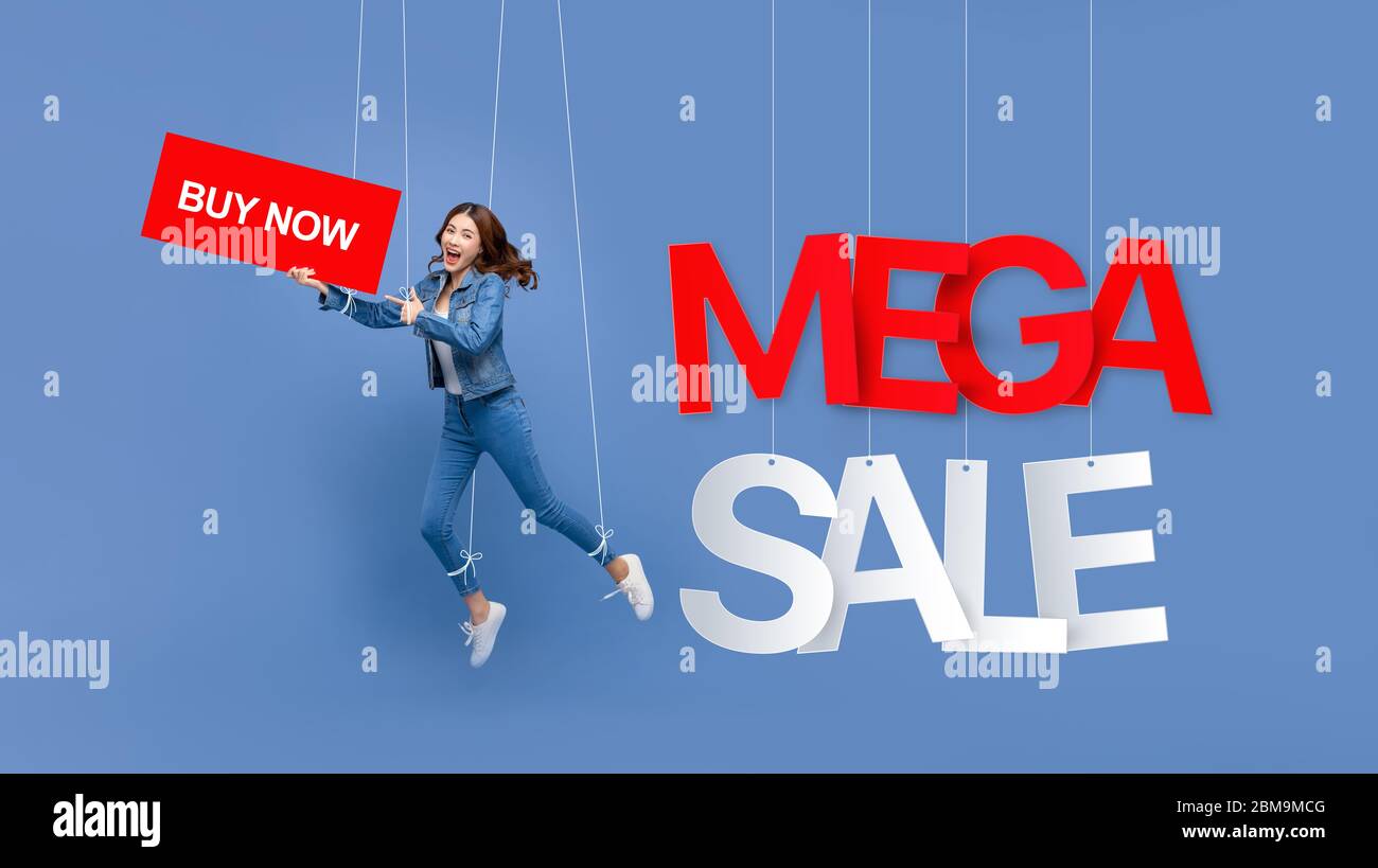 Eccitato bella donna asiatica pupet su corde tenuta ACQUISTA ora segno con MEGA VENDITA testi appesi su sfondo azzurro Foto Stock