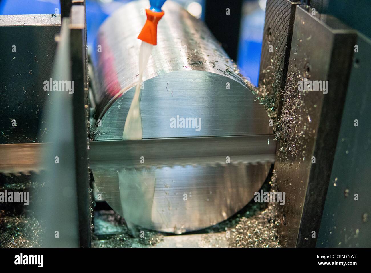 Un processo di taglio di barre cilindriche in alluminio con sega a nastro. Foto Stock
