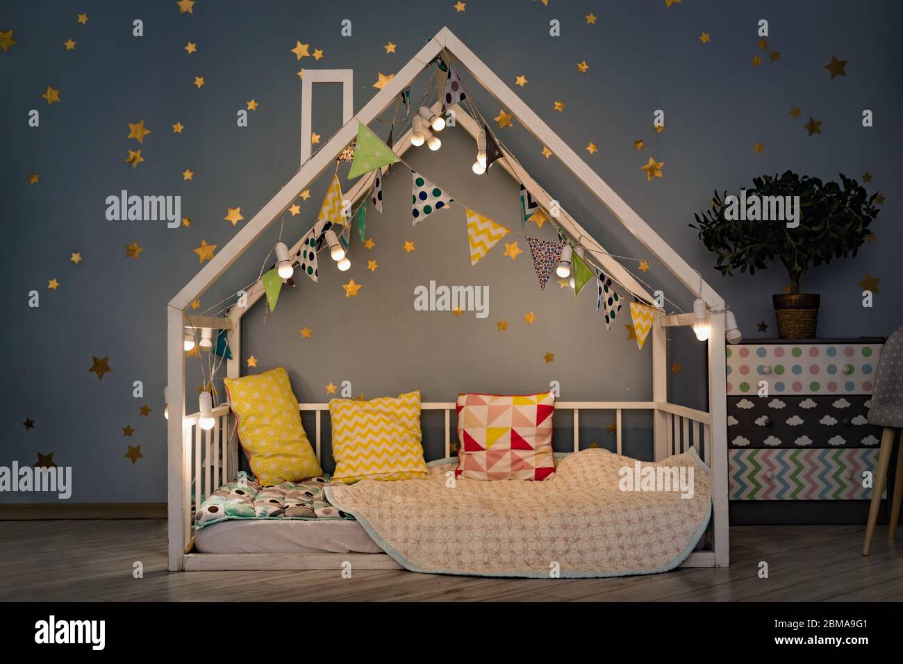 Camera per bambini moderna la sera. Casa letto decorata con luci garland Foto Stock