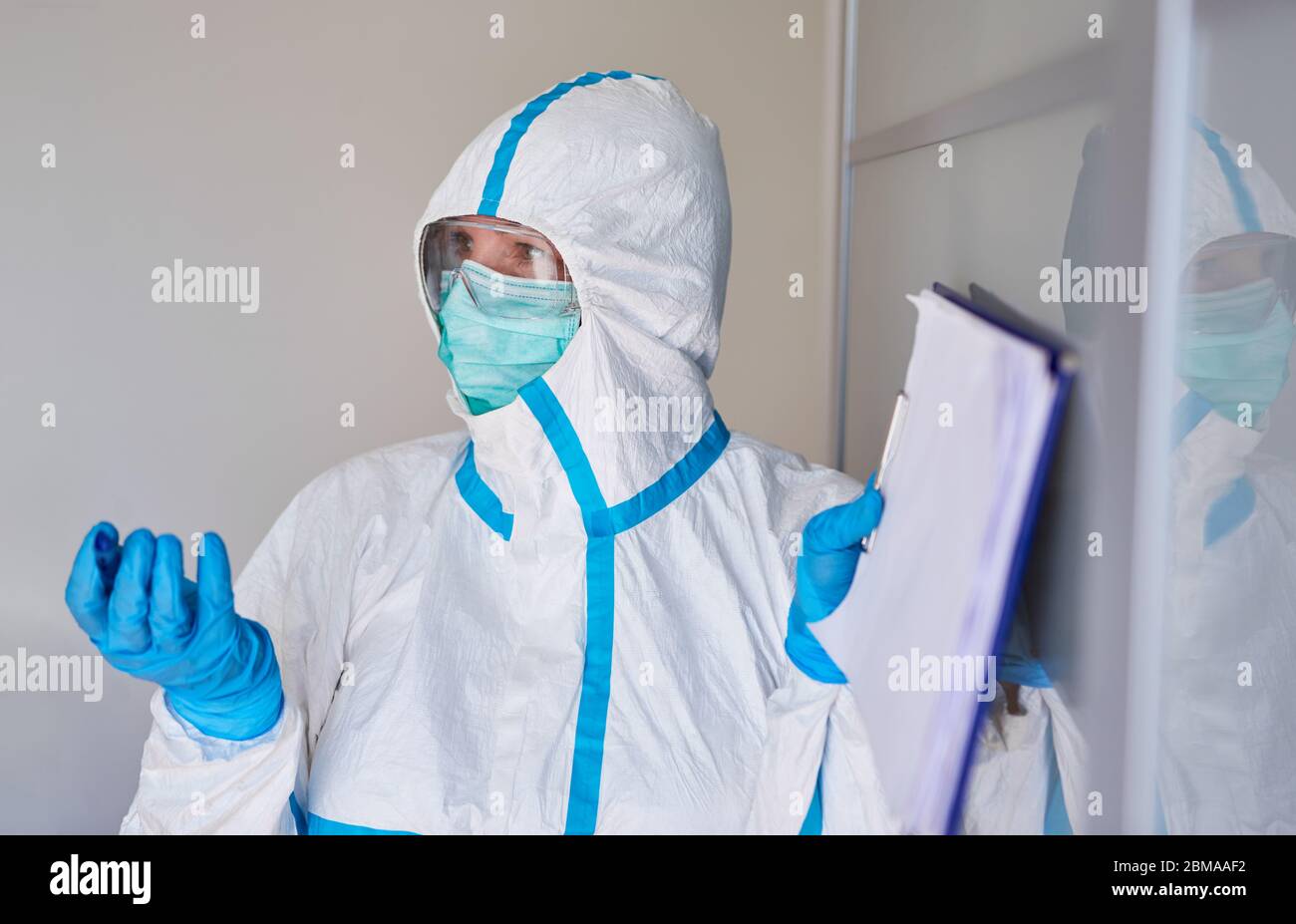 Personale sanitario in indumenti protettivi con un elenco di contatti per un caso sospetto di coronavirus Foto Stock