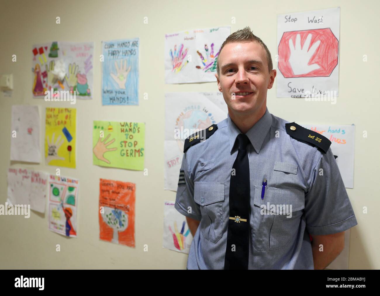 Il sergente John o'Reilly, di polizia comunitaria a Finglas, davanti all'opera d'arte dei bambini di un Garda sulla parete della stazione di Finglas Garda di Dublino. I membri di un Garda continuano a impegnarsi in un'ampia gamma di attività comunitarie, nel tentativo di aiutare le persone attraverso la pandemia del Covid-19, compresa la fornitura di medicinali per autoisolamento, la raccolta di pensioni, e fare lo shopping per la gente coconooning. Foto Stock