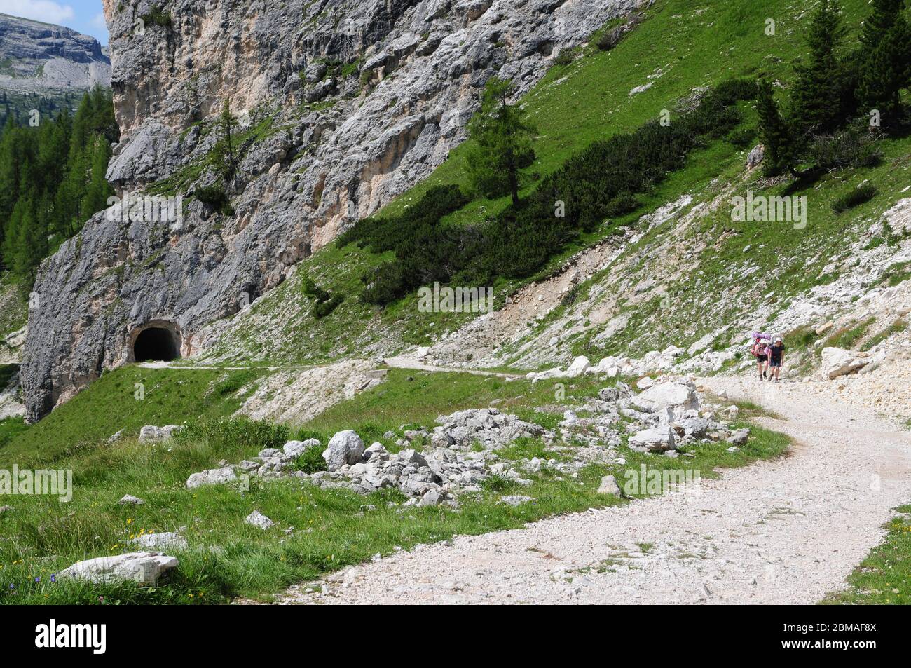 Escursionisti su una pista di montagna tra il Passo Falzarego e il col dei Bos nelle Dolomiti italiane. La pista e il tunnel risalgono alla seconda guerra mondiale. Foto Stock