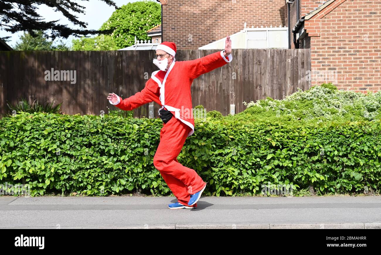 Littlehampton UK 8 maggio 2020 - un runner vestito da Babbo Natale che prende il suo esercizio di lock down a Rustington vicino Littlehampton durante le restrizioni di lock down del coronavirus COVID-19 pandemic. : Credit Simon Dack / Alamy Live News Foto Stock