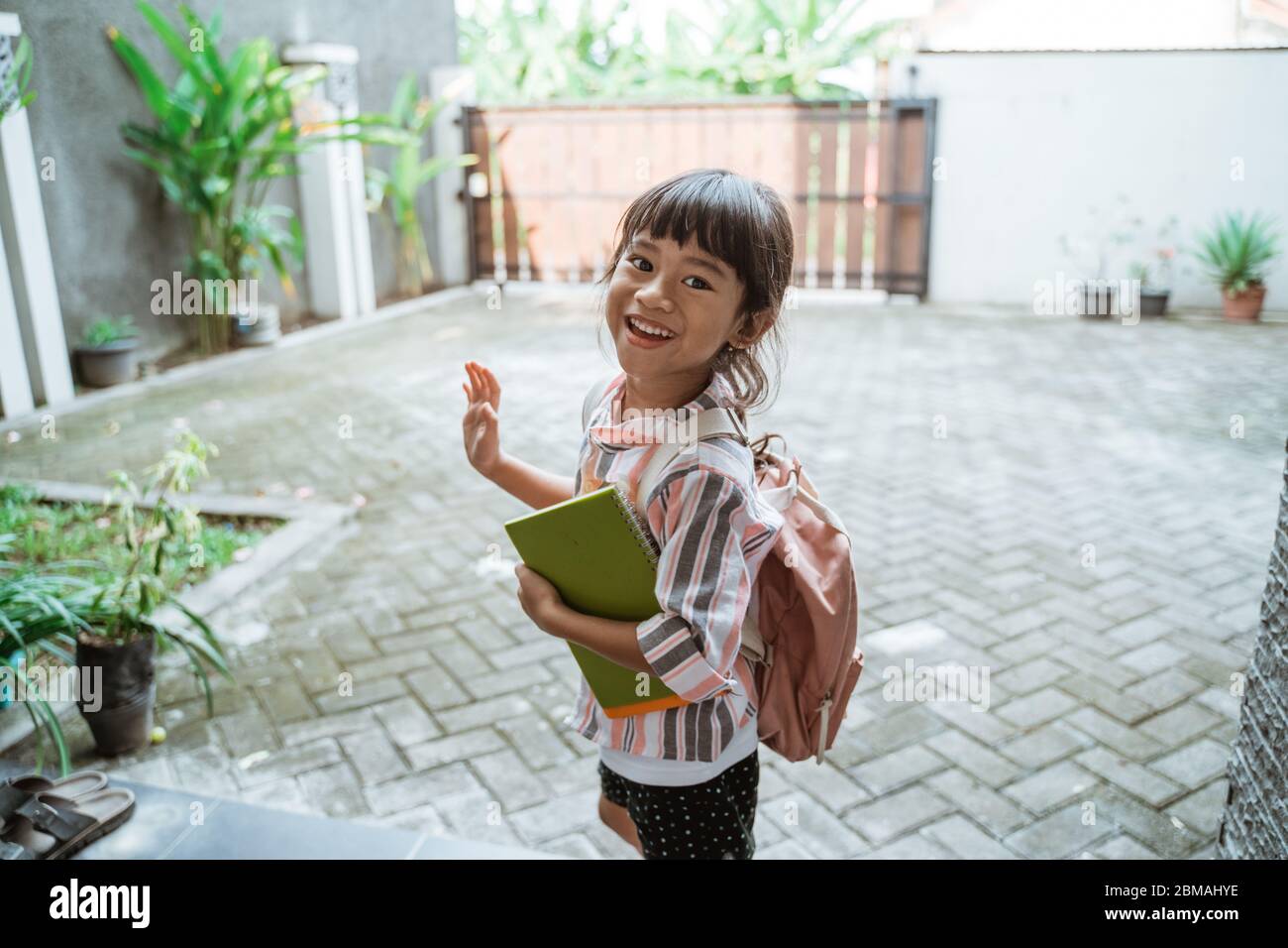 ragazzo felice agitare la mano prima di andare a scuola al mattino Foto Stock